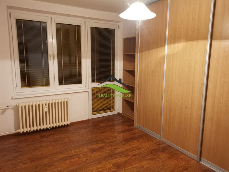 Pokoj s podlahou s dřevěným dekorem a velkou vestavěnou skříní v 3-pokojovém bytě.