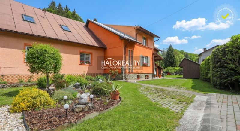 Rodinný dům v Dolní Marikové s barevnou fasádou obklopený zelenou zahradou a chodníkem.