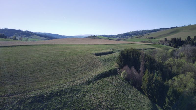 Krajina v okolí Čierneho Balogu se zemědělskými a lesními pozemky za jasného dne.