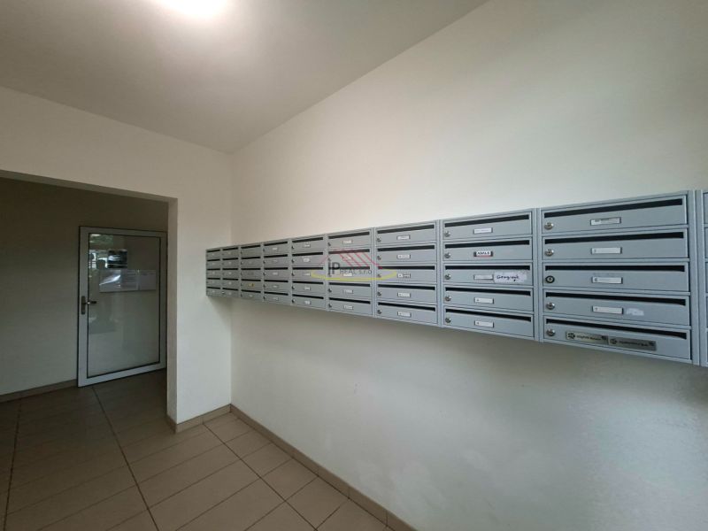 Poštovní schránky ve vstupní hale garsonky, podlaha s dlažbou, jednoduchý design.