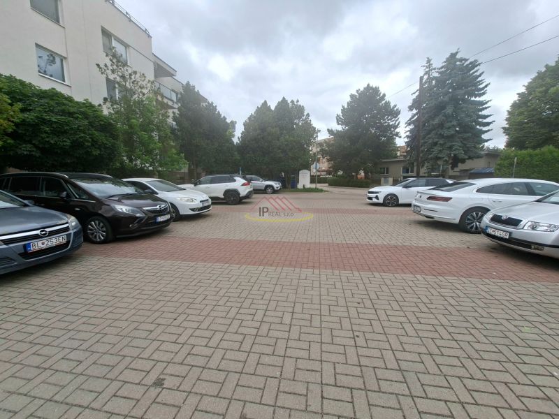 Parkoviště s auty na Športové ulici v Dunajské Lužné před budovou.