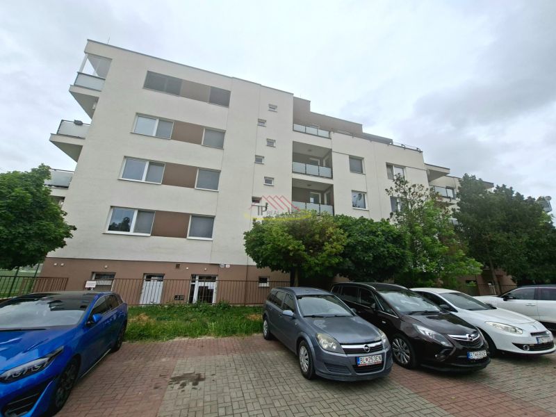 Bytový dům na Športové ulici v Dunajské Lužné s parkovištěm a auty před budovou.