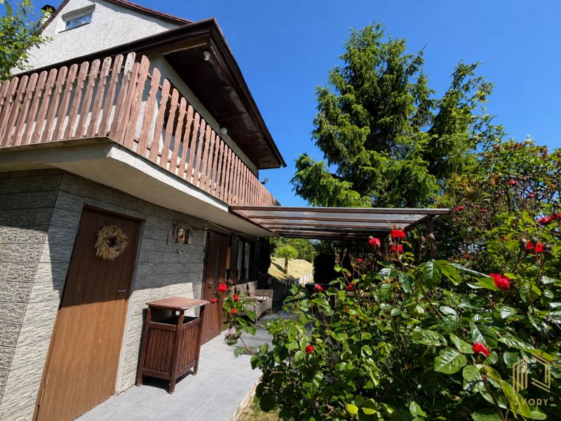 Chata v Kunově u Senice obklopená zelení a květinami s dřevěnými prvky.