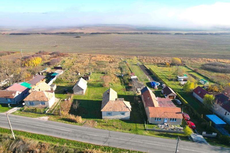 Domy u hlavní silnice v Radnovcích, s pozemky - bydlení obklopené poli.