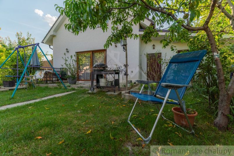 Zahrada rodinného domu v Bernolákově s houpačkou, zahradním nábytkem a zelení.