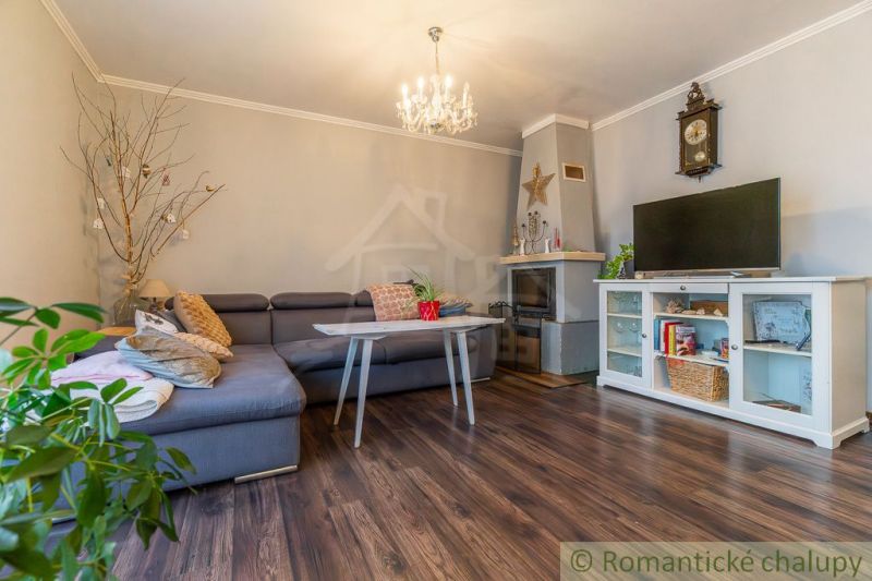 Obývací pokoj v rodinném domě s krbem, rohovou sedačkou a podlahou s dřevěným dekorem.