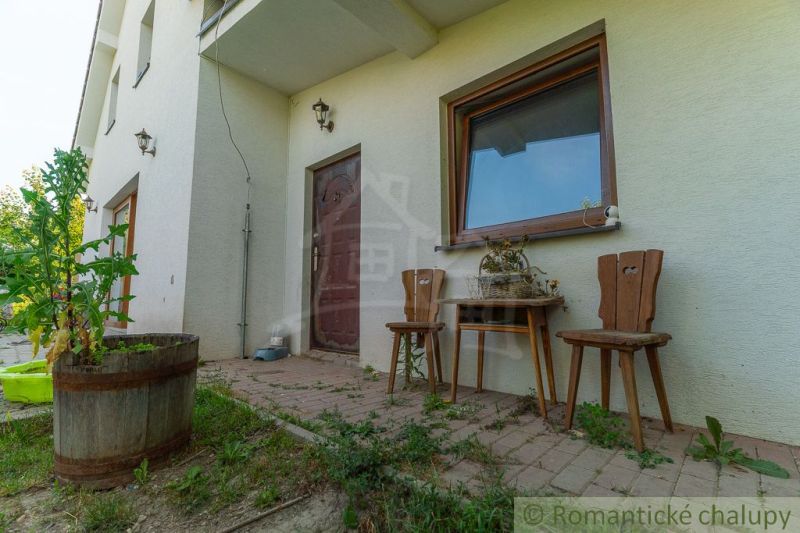Exteriér rodinného domu v Bernolákově s terasou a dřevěným nábytkem.