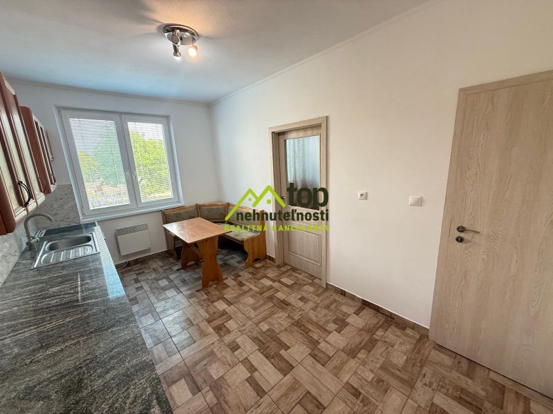 Kuchyně se světlým nábytkem a dlaždicovou podlahou v 2-pokojovém bytě.