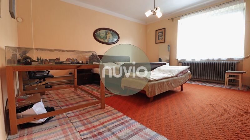 Ložnice s jemně oranžovým kobercem a modelovou železnicí v rodinném domě.