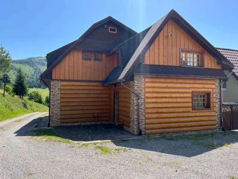 Rodinný dům ve Velkém Borovém s dřevem a kamenem obloženým exteriérem u lesa.