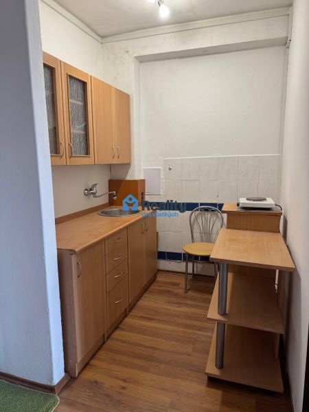 Kompaktní kuchyně v 2pokojovém bytě se světlým nábytkem a podlahou s dřevěným dekorem.