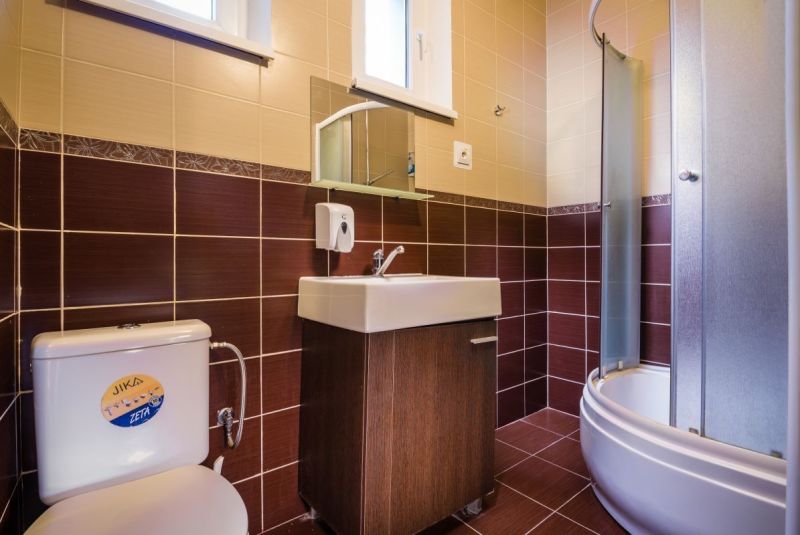 Koupelna s vanou, umyvadlem a toaletou v hotelu a penzionu.