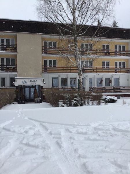 Hotel a penzion v Liptovském Jánu se zasněženou střechou a exteriérem.