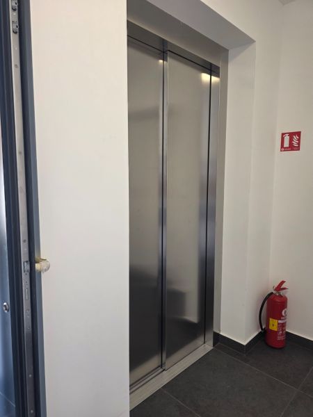 Výtah ve 4-pokojovém bytě s dlažbou a hasicím přístrojem.