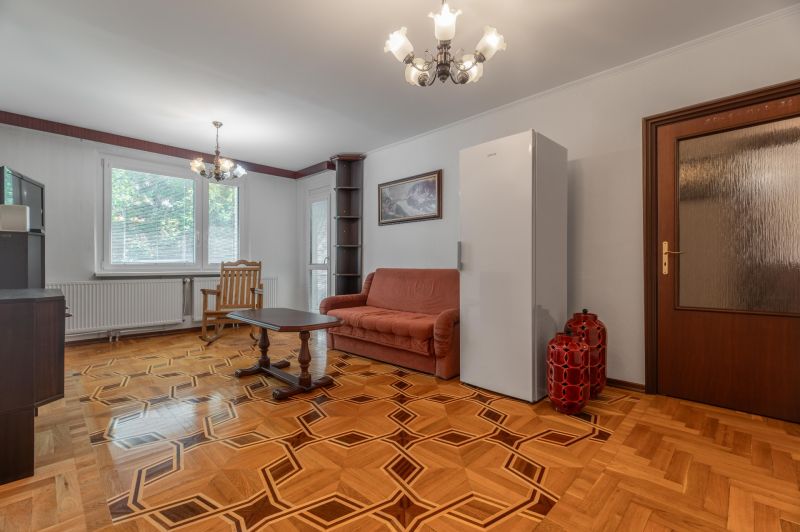 Obývací pokoj s pohovkou, stolkem a podlahou s dřevěným dekorem ve 3pokojovém bytě.