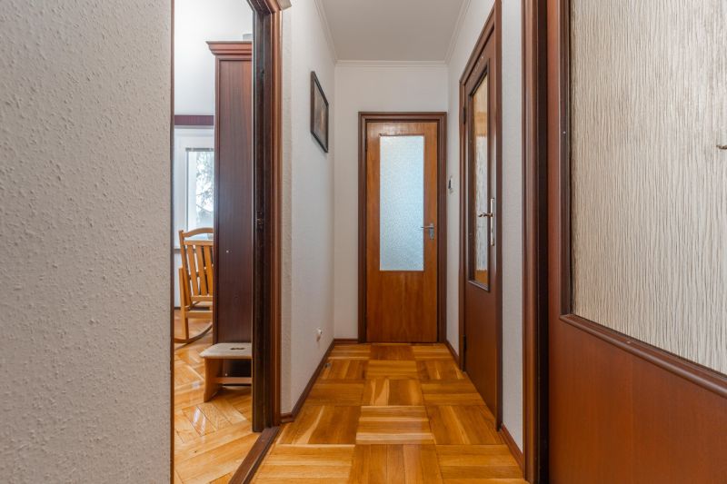 Chodba s podlahou s dřevěným dekorem v 3-pokojovém bytě, vedoucí do místnosti.