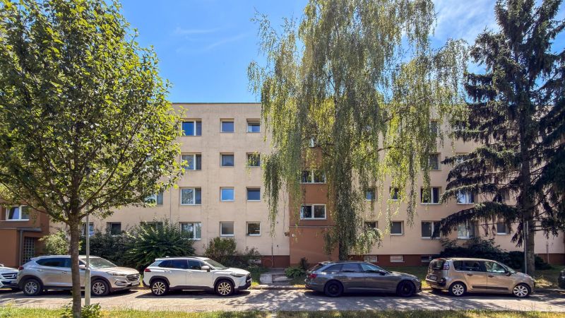 Bytový dům na ulici Staré zahrady v Bratislavě - Ružinově obklopený zelení a auty.