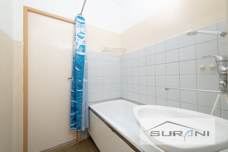 Koupelna s vanou a modrým sprchovým závěsem ve 4pokojovém bytě.