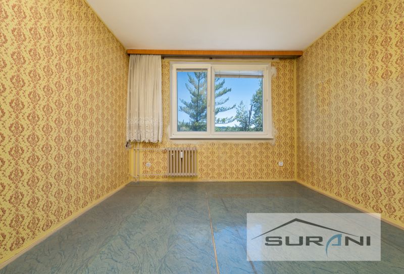 Pokoj s texturovanými tapetami, modrou podlahou a oknem ve 4-pokojovém bytě.