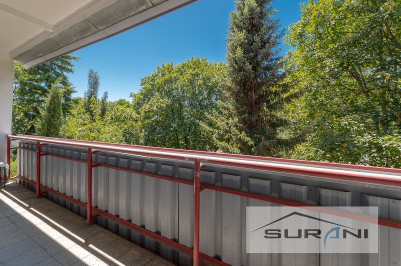 Balkon ve 4pokojovém bytě s výhledem na zeleň a modrou oblohu.