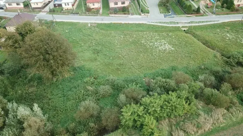 Travnaté pozemky pro bydlení ve Slovenské Volové obklopené zelení a domy.