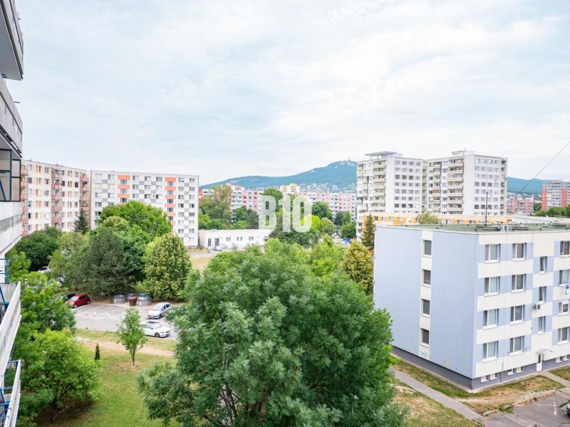 Výhled z 3pokojového bytu v Nitře na panelové domy a parkoviště s automobily.