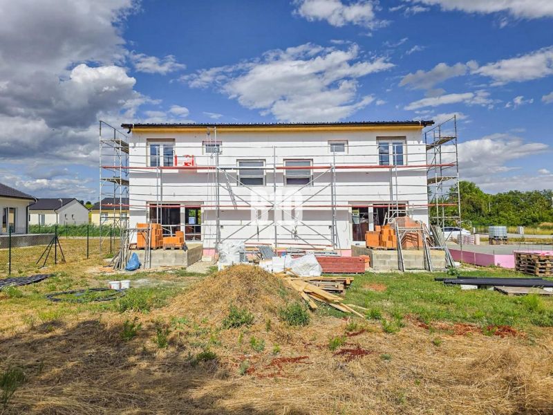 Stavba rodinného domu v Nitře s rozestavěným lešením a materiály na pozemku.