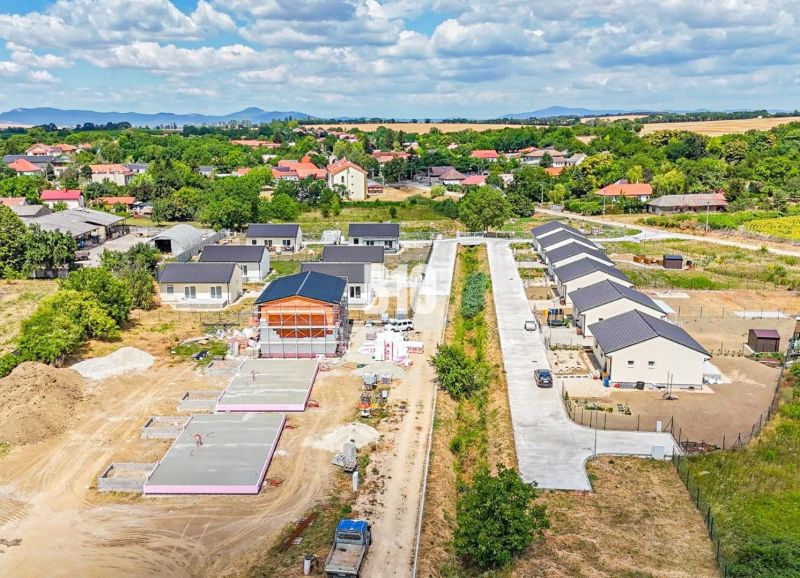 Výstavba rodinných domů v Nitře obklopená zelenou krajinou a dalšími nemovitostmi.