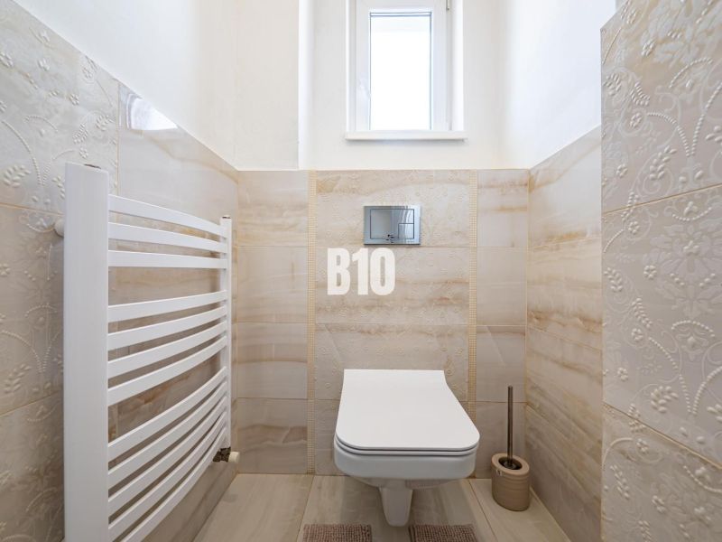Koupelna v rodinném domě obsahuje závěsné WC, dlažbu a radiátor.