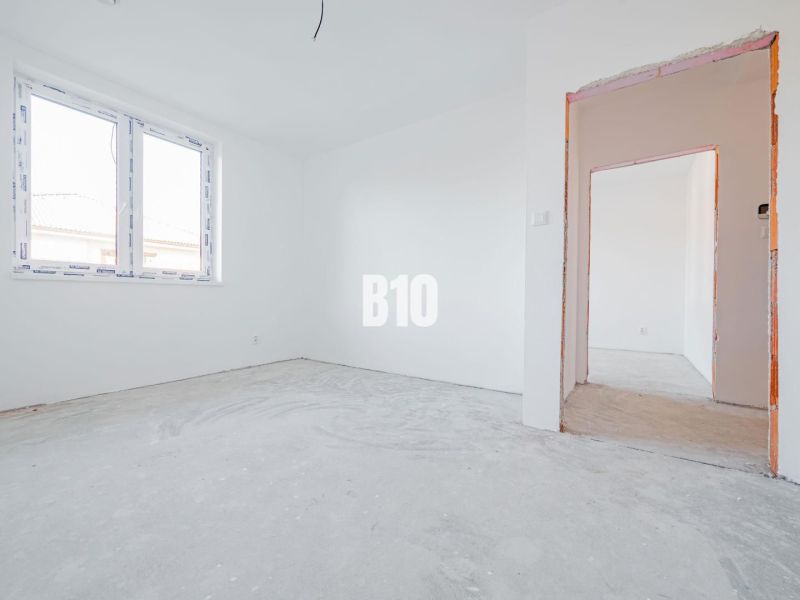 Interiér rodinného domu s bílými stěnami a betonovou podlahou.
