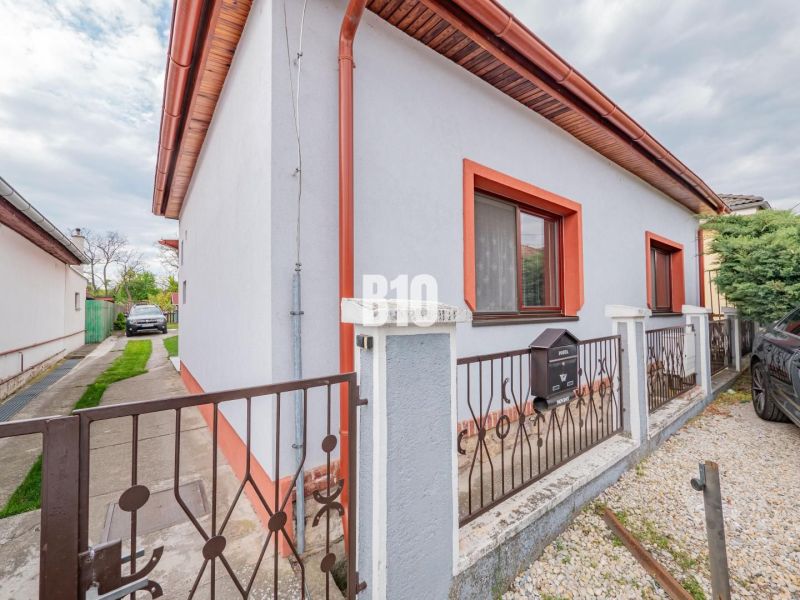 Rodinný dům v Nitře s bílou fasádou, červeným lemováním a zahrádkou.