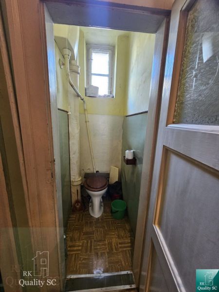 Toaleta v 2-pokojovém bytě s oknem a podlahou s dřevěným dekorem.