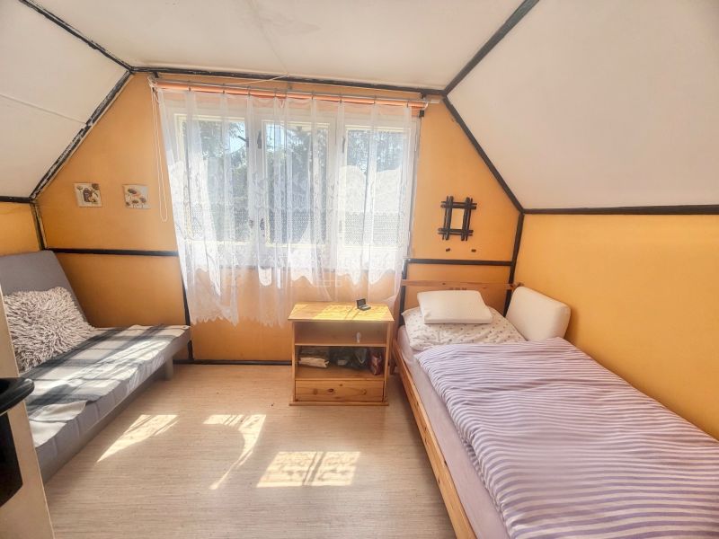 Interiér chaty s dvěma lůžky, stolkem a dekoracemi na stěnách.