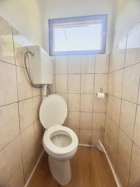 Toaleta v chatě s oknem a podlahou s dřevěným dekorem.