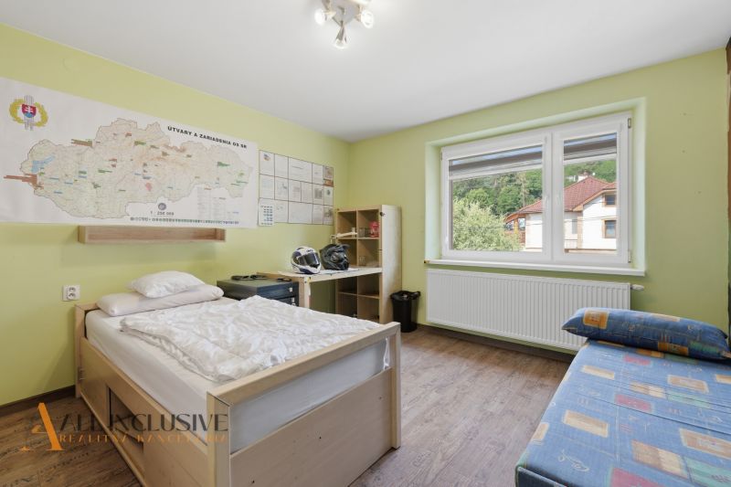 Pokoj v rodinném domě s mapou na stěně, postelí a podlahou s dřevěným dekorem.