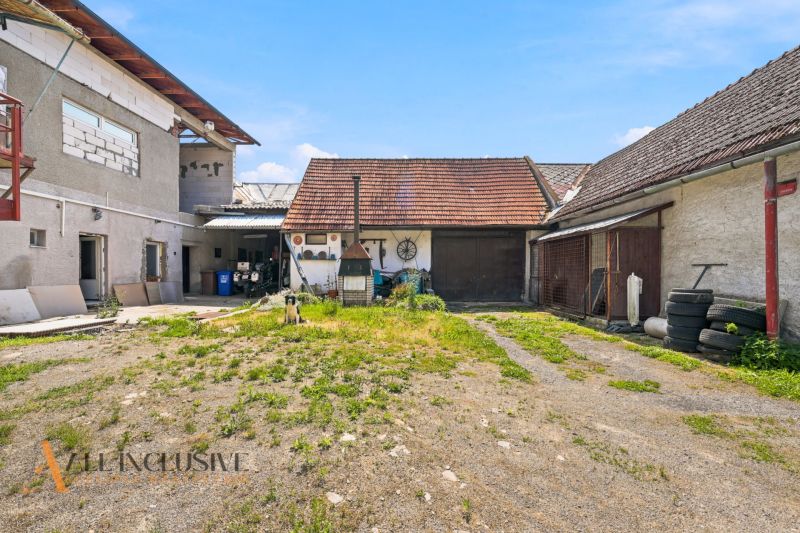 Dvůr rodinného domu v Dúbravici s hospodářskými budovami a psem na pozemku.