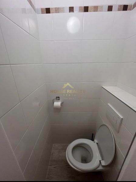 Toaleta s bílými obklady a mozaikovým dekorem v 1-pokojovém bytě.
