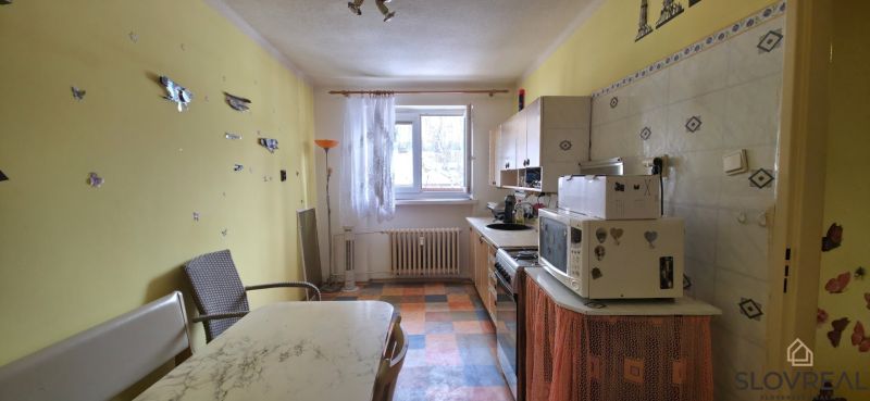 Kuchyně v 2-pokojovém bytě se žlutými stěnami a kostkovanou podlahou.