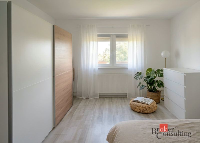Světlá ložnice ve 4-pokojovém bytě s minimalistickým nábytkem a podlahou s dřevěným dekorem.