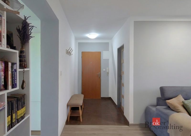 Chodba ve 4-pokojovém bytě s lavicí a knihovničkou.
