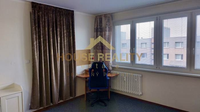 Stůl u okna v garsonce se závěsy a výhledem.