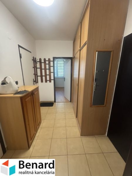 Chodba s úložnými skříněmi a dlažbou v 2-pokojovém bytě.