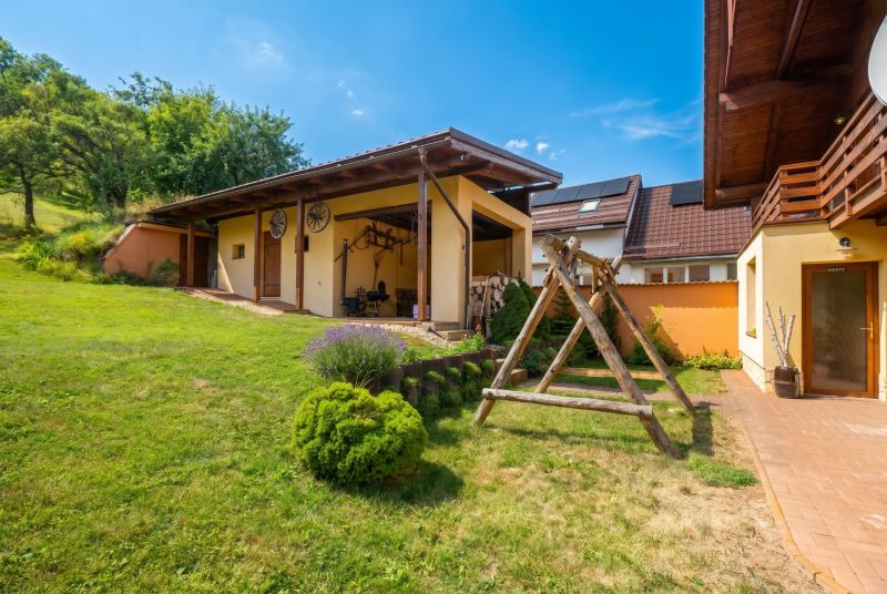 Rodinný dům v Horní Lhotě s dřevěným přístřeškem a velkým travnatým dvorem.