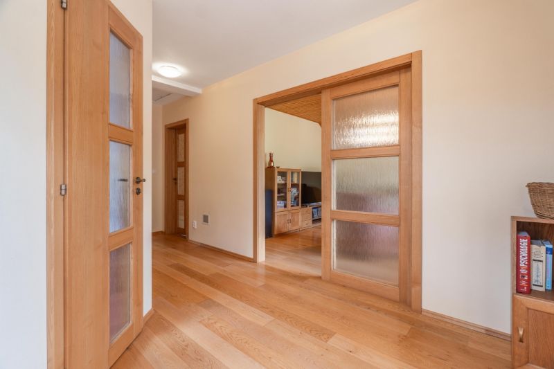 Chodba rodinného domu s dřevěnými dveřmi a podlahou s dřevěným dekorem.