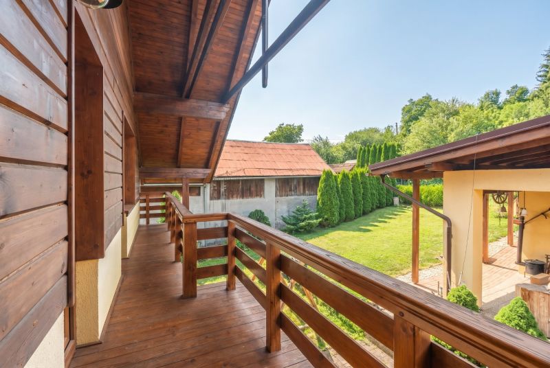 Rodinný dům v Horní Lehotě s dřevěným balkonem a zahradou se stromy.