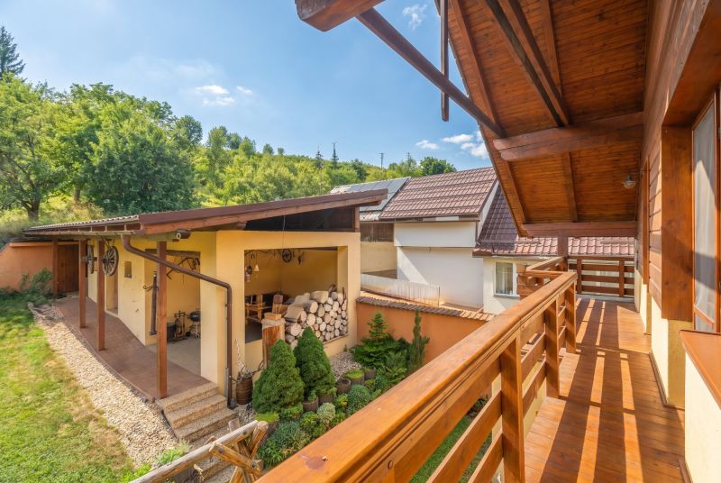 Balkon rodinného domu v Horní Lehotě, dřevěné zábradlí, zahrada a kůlna.