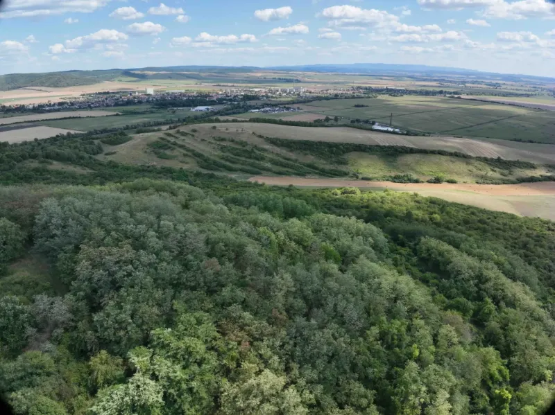 Krajina v Tornaľi se smíšenými zemědělskými a lesními pozemky pod jasnou oblohou.