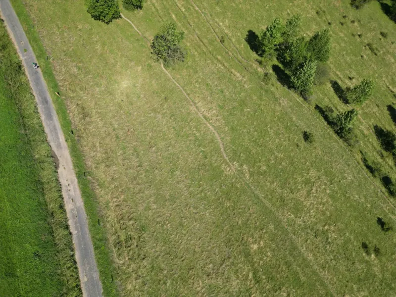 Letecký snímek krajiny u Staré Ľubovně, zvýrazňující zelené louky a stromovou scenérii.