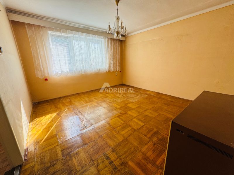 Pokoj v 2-pokojovém bytě s křišťálovým lustrem a podlahou s dřevěným dekorem.