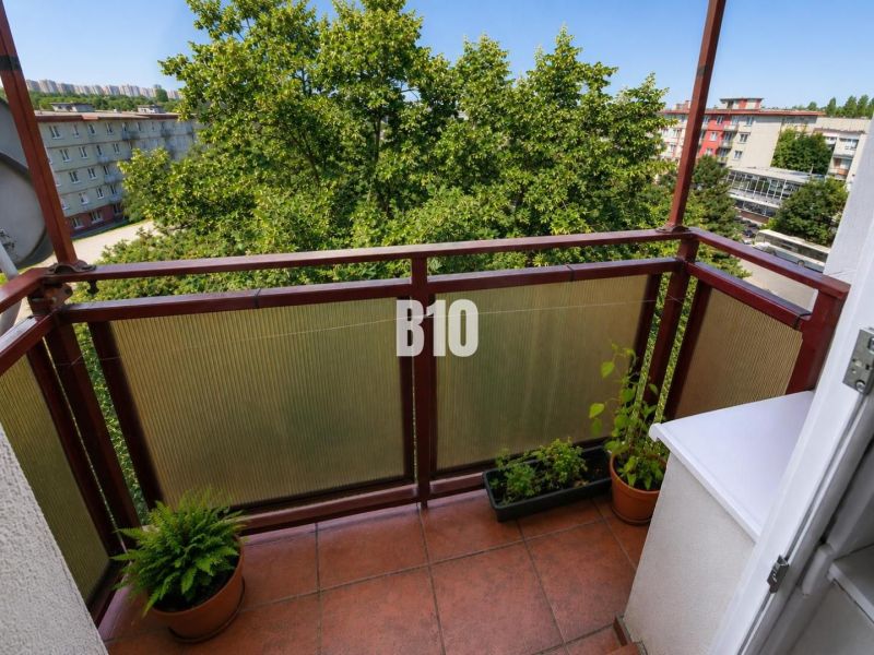Balkon 2-pokojového bytu v Nitře s výhledem na zelení obklopené sídliště.